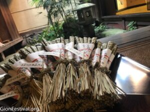 A small pile of woven grass "chimaki" talismans in front of a Japanese garden.