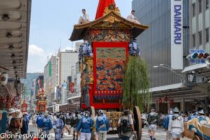 Several colorful Gion Festival floats are pulled down a central Kyoto street.