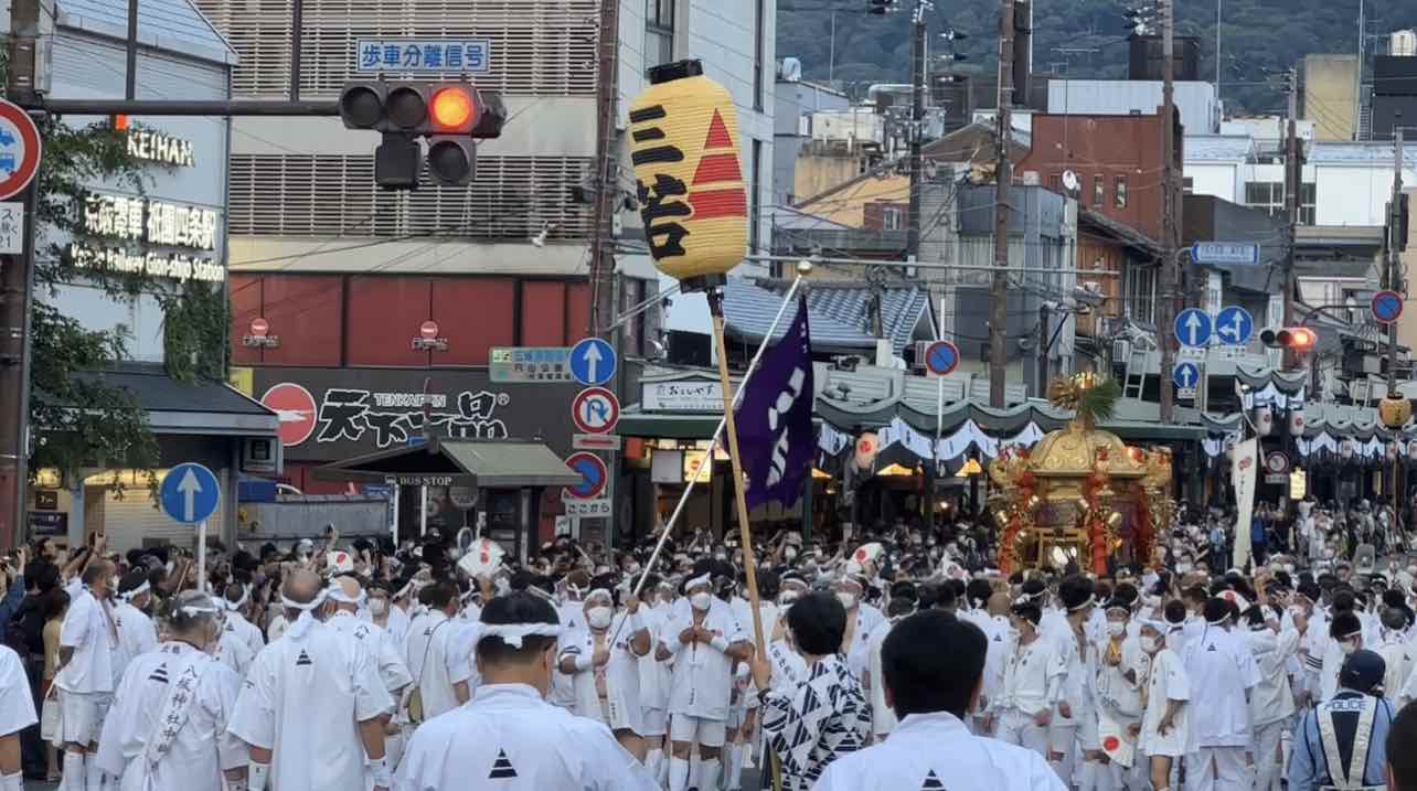 A portable mikoshi shrine is carried by scores of men down a main street in Kyoto as part of the Gion Festival.