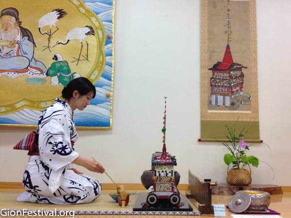 A Japanese woman dressed in yukata kneels to perform tea ceremony at Kikusui Boko.