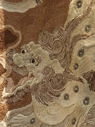 A vintage, embroidered textile of a  lion dog